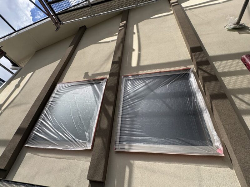 外壁塗装前に窓ガラスとサッシをビニールシートとテープで保護した養生作業